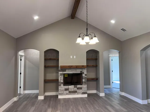 a view of a room with a fireplace wooden floor and chandelier