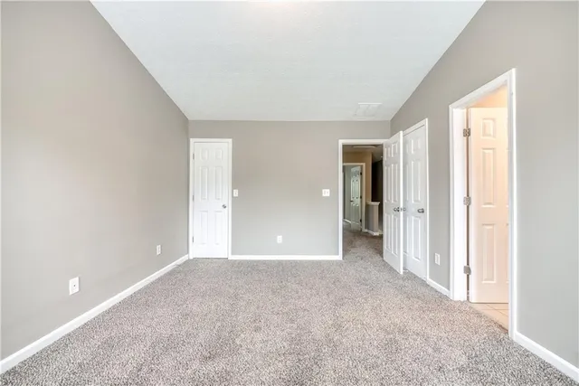 a view of an empty room with closet and a window
