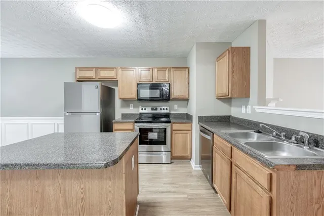 a kitchen with stainless steel appliances granite countertop a sink stove and refrigerator