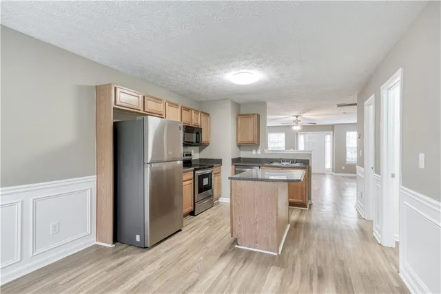 a kitchen with granite countertop a refrigerator stove and wooden floor