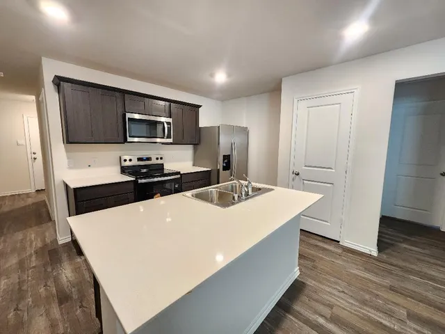 a kitchen with kitchen island wooden cabinets a sink and a stove