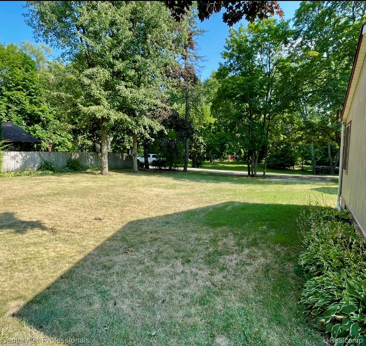 2903 Lake Angelus Road Waterford, MI 48329 - Photo 16 of 17 Expansive backyard with a mix of green and drier lawn areas, mature perimeter trees, and a weathered wood fence