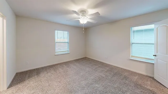 an empty room with windows and fan