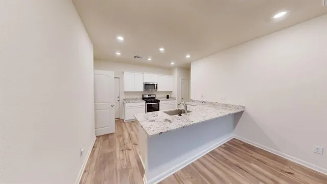 a large kitchen with kitchen island a sink white cabinets and stainless steel appliances