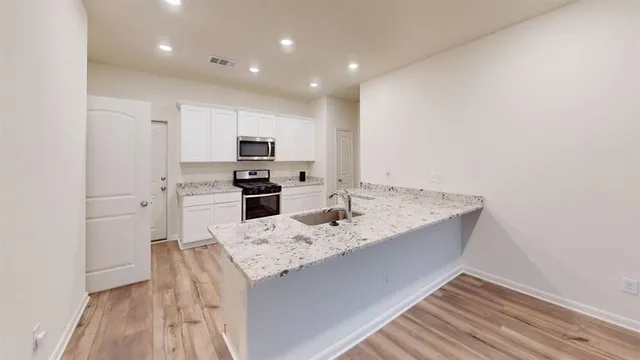a kitchen with granite countertop a sink stove and refrigerator