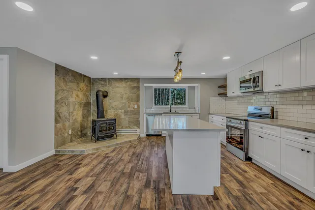 a kitchen with kitchen island a counter top space a sink stainless steel appliances and cabinets