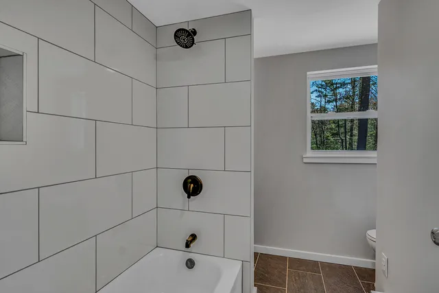 a view of an empty room with wooden floor and window