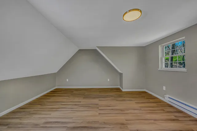 a view of an empty room with wooden floor and window
