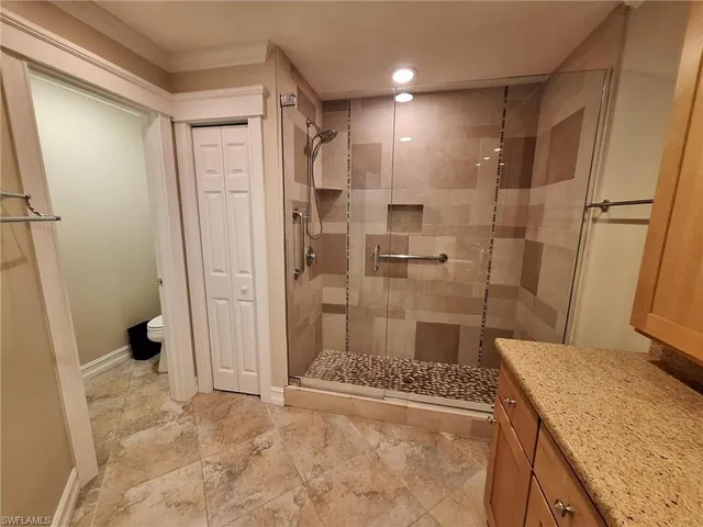 a bathroom with a granite countertop sink a toilet and shower