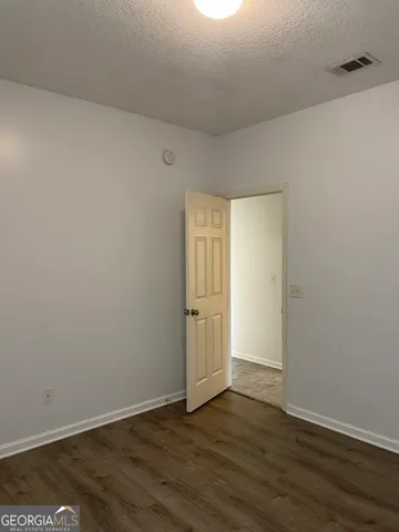 a view of an empty room with wooden floor and closet