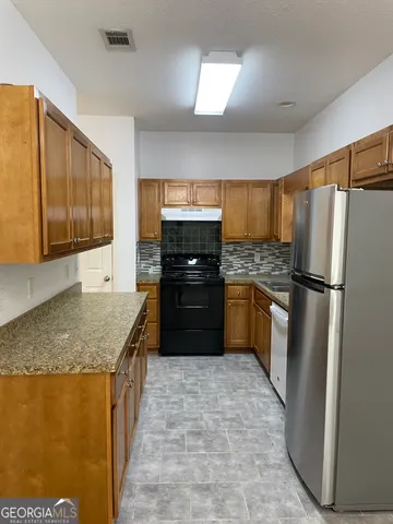 a kitchen with granite countertop a refrigerator and a sink