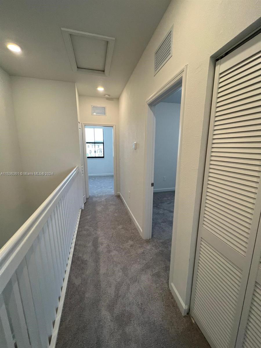 11774 Southwest 246th Street, Unit 11774 Homestead, FL 33032 - Photo 9 of 17 a view of a hallway to a room with wooden stairs