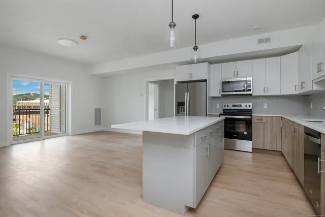 a large kitchen with stainless steel appliances granite countertop a stove a sink and a refrigerator