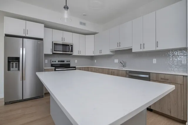 a kitchen with stainless steel appliances a refrigerator sink and white cabinets