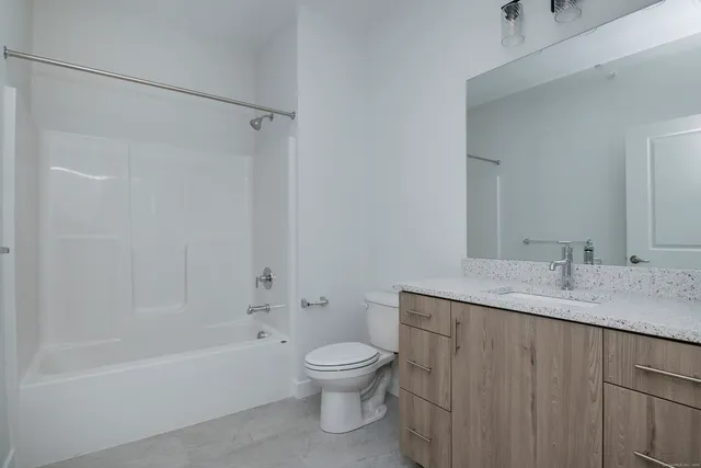 a bathroom with a granite countertop sink a toilet and shower