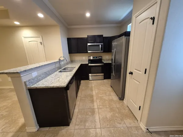 a kitchen with granite countertop a refrigerator and a sink