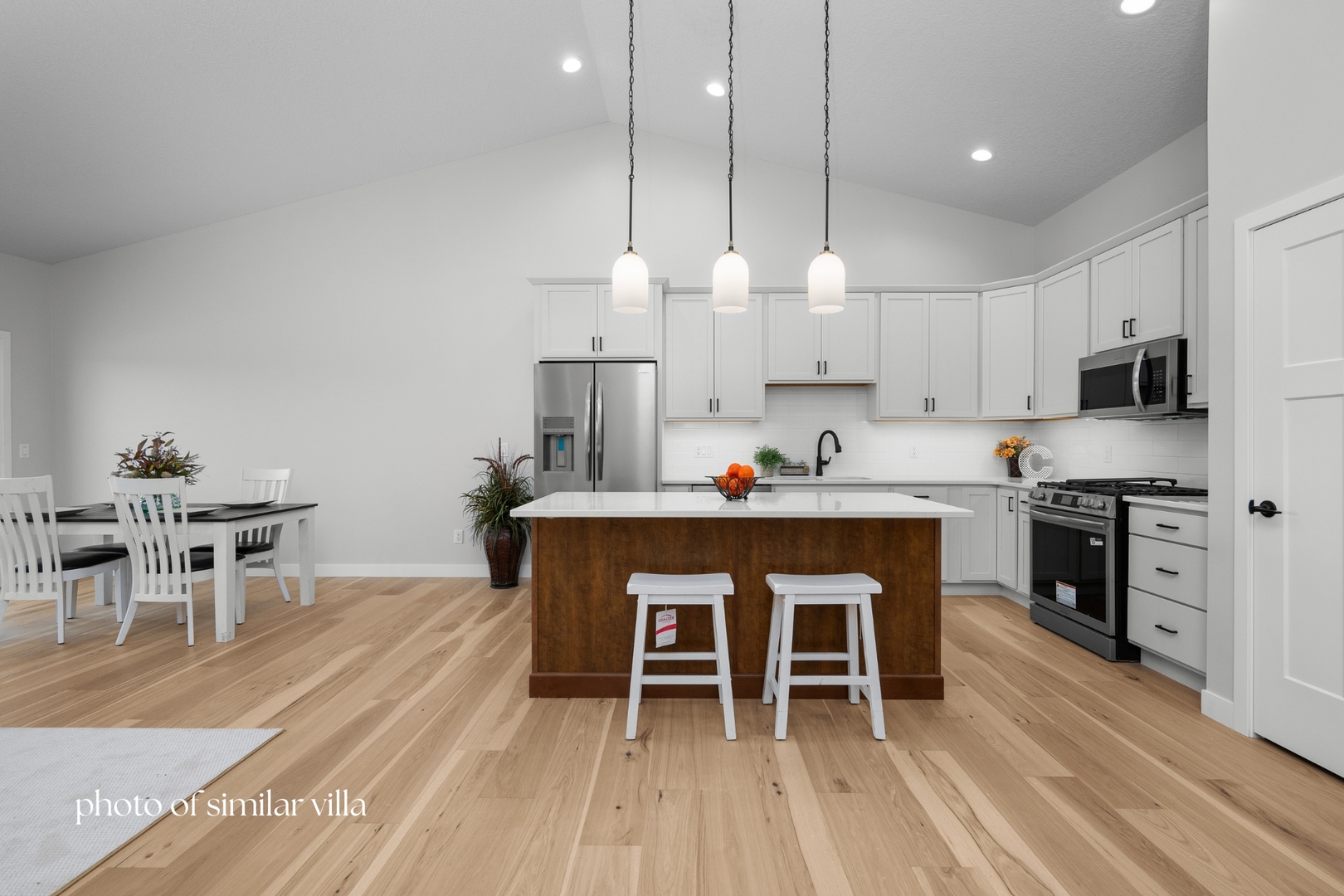1867 Redbud Circle, Unit 101 Eldridge, IA 52748 - Photo 13 of 31 a kitchen with stainless steel appliances a dining table chairs stove and white cabinets