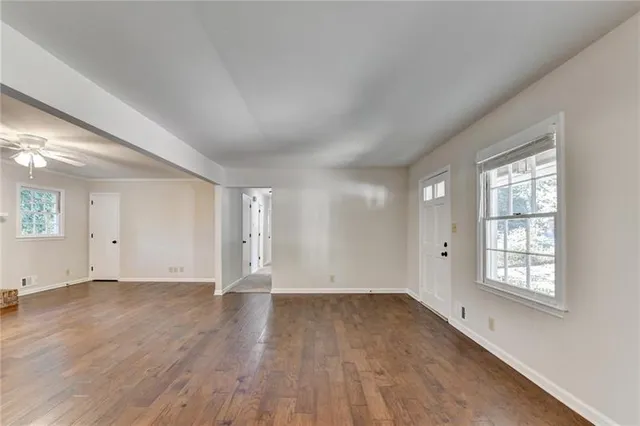 an empty room with wooden floor and windows