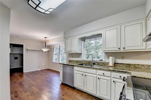 a kitchen with granite countertop white cabinets stainless steel appliances and a sink