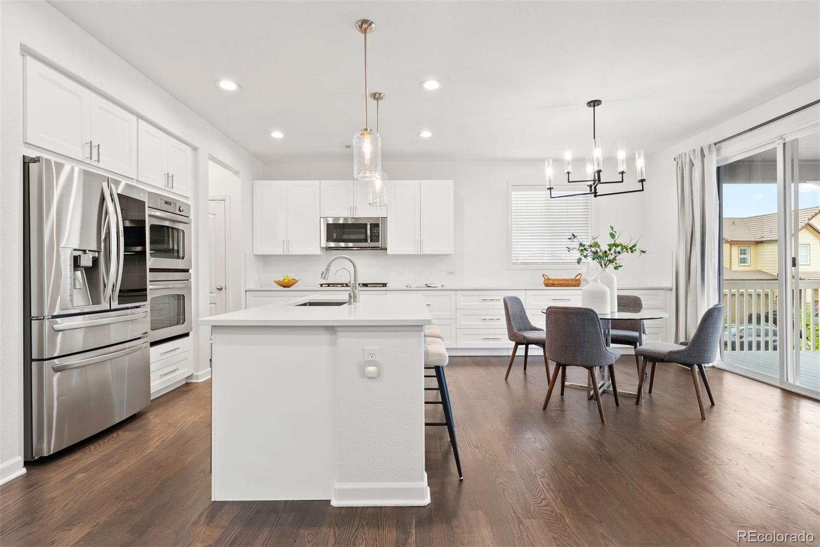 664 Tiger Lily Way Highlands Ranch, CO 80126 - Photo 11 of 47 a kitchen with stainless steel appliances granite countertop a refrigerator stove a dining table and chairs with wooden floor