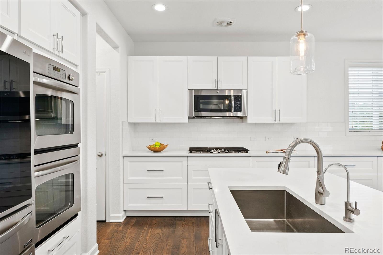 664 Tiger Lily Way Highlands Ranch, CO 80126 - Photo 8 of 47 a kitchen with stainless steel appliances a stove a sink a microwave and wooden cabinets