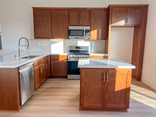 a kitchen with stainless steel appliances granite countertop wooden cabinets a refrigerator a sink and a stove