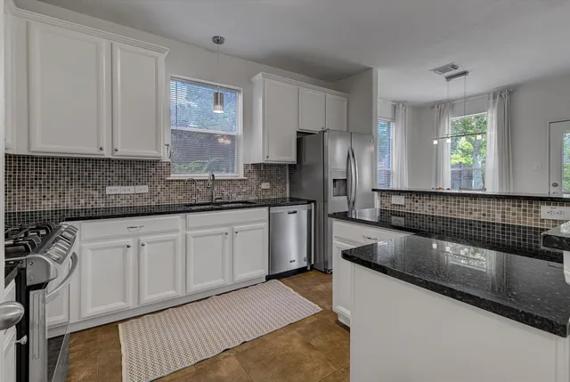 a kitchen with granite countertop white cabinets and stainless steel appliances