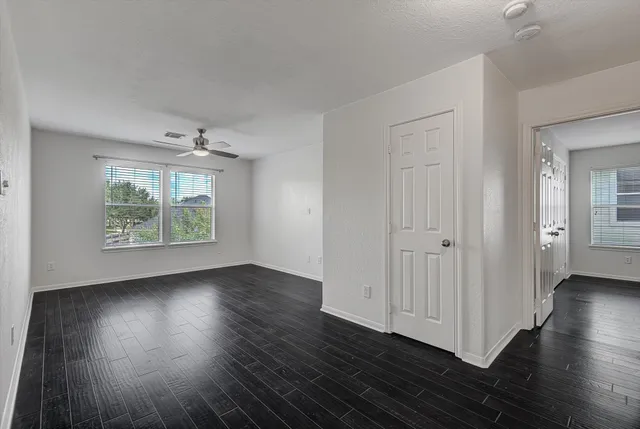 an empty room with wooden floor and windows