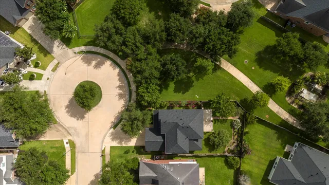 an aerial view of a house with a yard and trees all around