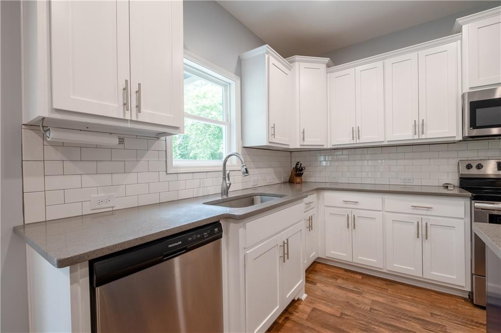 719 Fairview Road Brooks, GA 30205 - Photo 15 of 35 a kitchen with stainless steel appliances granite countertop a sink dishwasher a stove and white cabinets with wooden floor