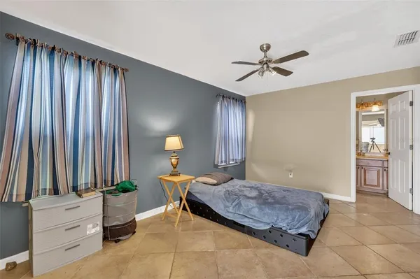 a bedroom with a large bed and a chandelier fan