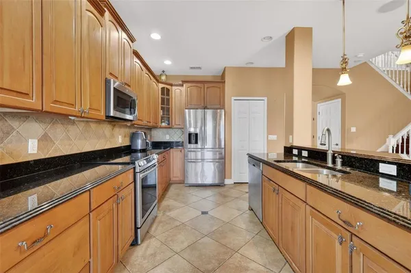 a large kitchen with stainless steel appliances granite countertop a sink a stove and a refrigerator