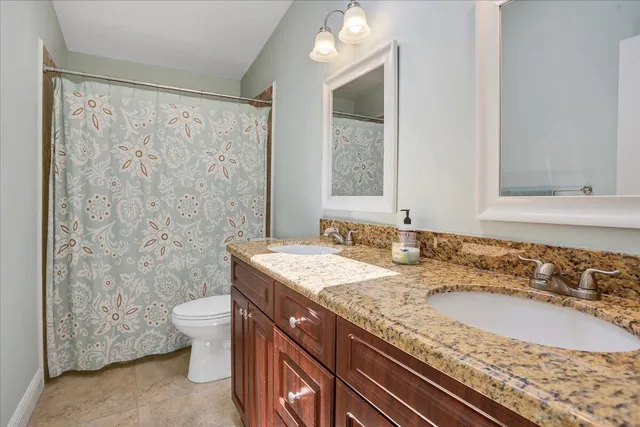 a bathroom with a granite countertop sink a toilet a mirror and shower