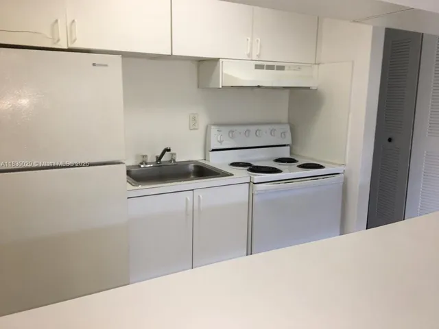 a kitchen with kitchen island a sink a stove and a refrigerator