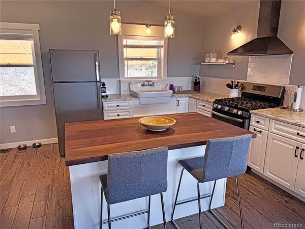 a kitchen with a table chairs a stove a window and wooden floor