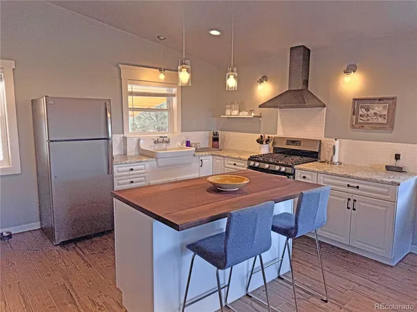 a kitchen with stainless steel appliances a stove a refrigerator a sink a stove white cabinets and chairs