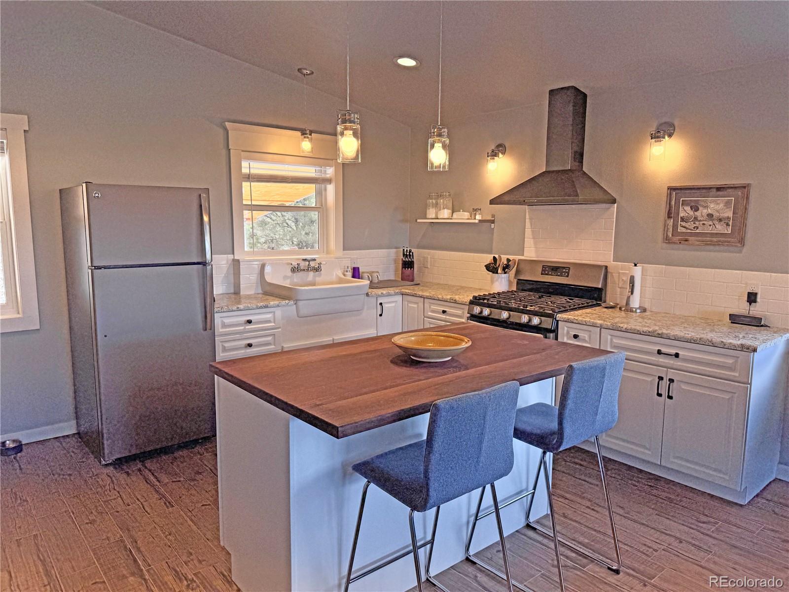 563 Kankakee Road Westcliffe, CO 81252 - Photo 8 of 46 a kitchen with stainless steel appliances a stove a refrigerator a sink a stove white cabinets and chairs