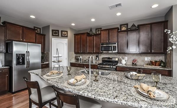 4308 Perth Road, Unit 320 Indian Land, SC 29707 - Photo 2 of 11 a kitchen with stainless steel appliances granite countertop a kitchen island a table and chairs in it