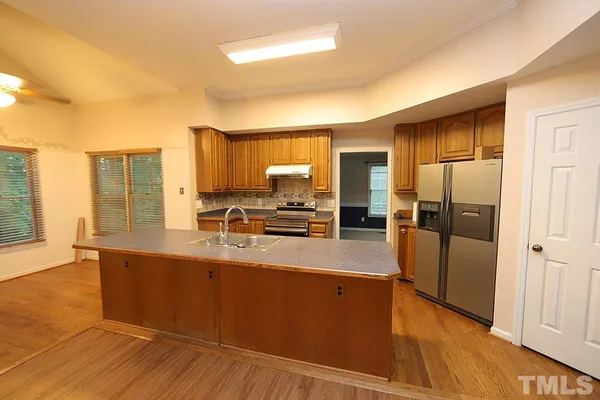 a kitchen with stainless steel appliances granite countertop a refrigerator a stove and a wooden floors