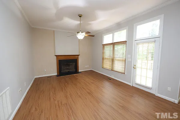 an empty room with wooden floor fireplace and windows