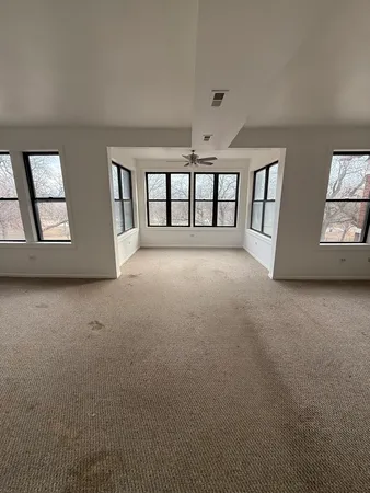 an empty room with windows and ceiling fan