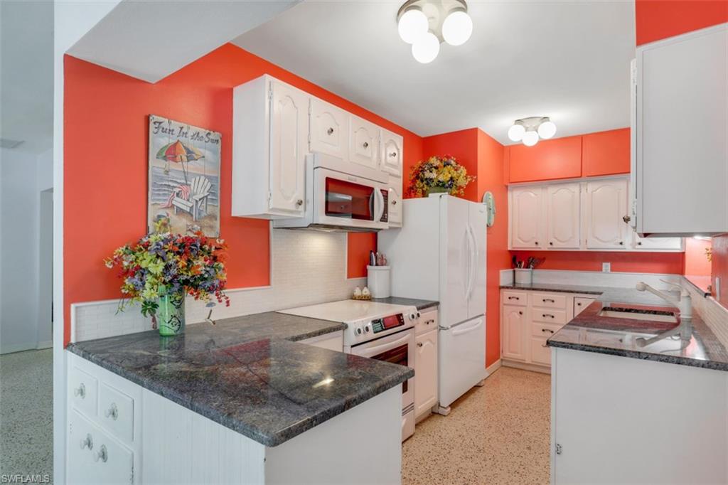 409 3rd Avenue North Naples, FL 34102 - Photo 24 of 41 a kitchen that has a microwave a stove and white cabinets