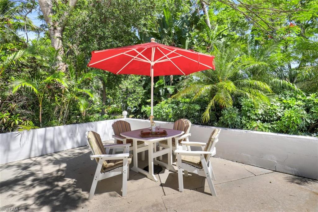409 3rd Avenue North Naples, FL 34102 - Photo 35 of 41 a patio with a table and chairs under an umbrella