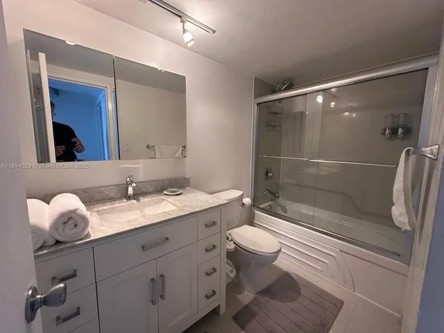 a bathroom with a granite countertop sink a toilet and shower