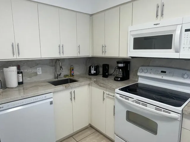 a kitchen with white cabinets and sink