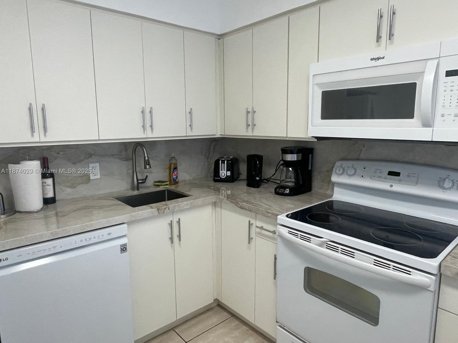 5151 Collins Avenue, Unit 1525 Miami Beach, FL 33140 - Photo 7 of 17 a kitchen with white cabinets and sink