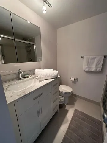 a bathroom with a granite countertop sink a toilet and a mirror