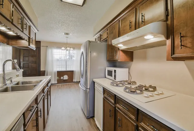 a kitchen that has a sink a stove and a refrigerator