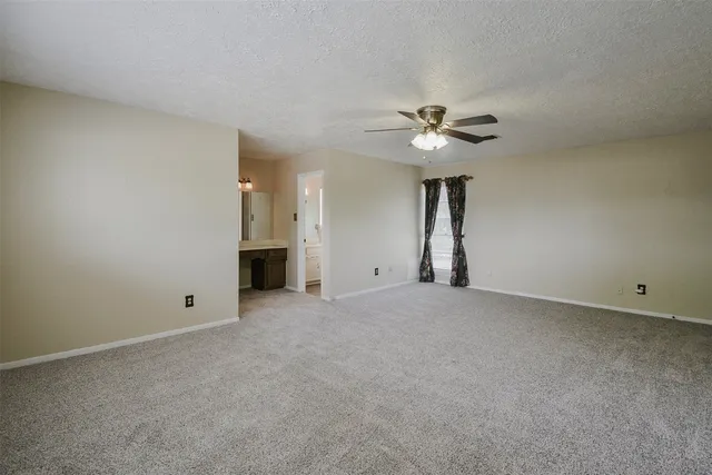 a view of an empty room with chandelier fan