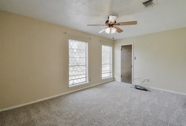 an empty room with windows and fan